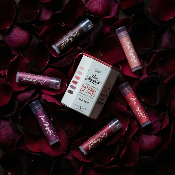 Set of lip tint tubes and packaging on red rose petals