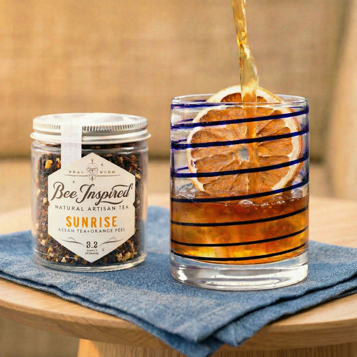 Bee Inspired tea jar with a glass of iced tea on a wooden surface