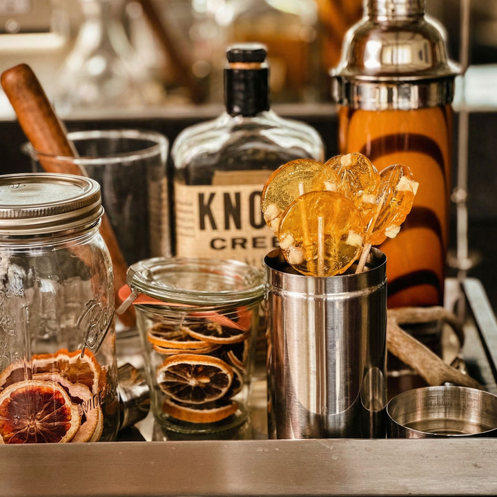 Bar setup with bottles, glasses, and cocktail shaker on a bar counter.