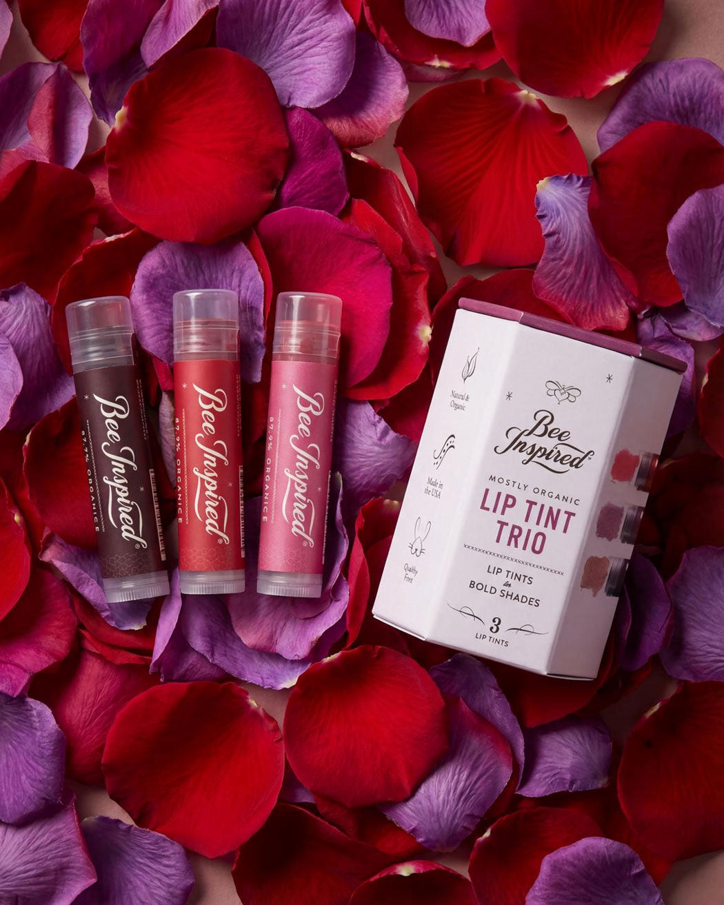 Lip tint trio with packaging on a bed of red and purple rose petals