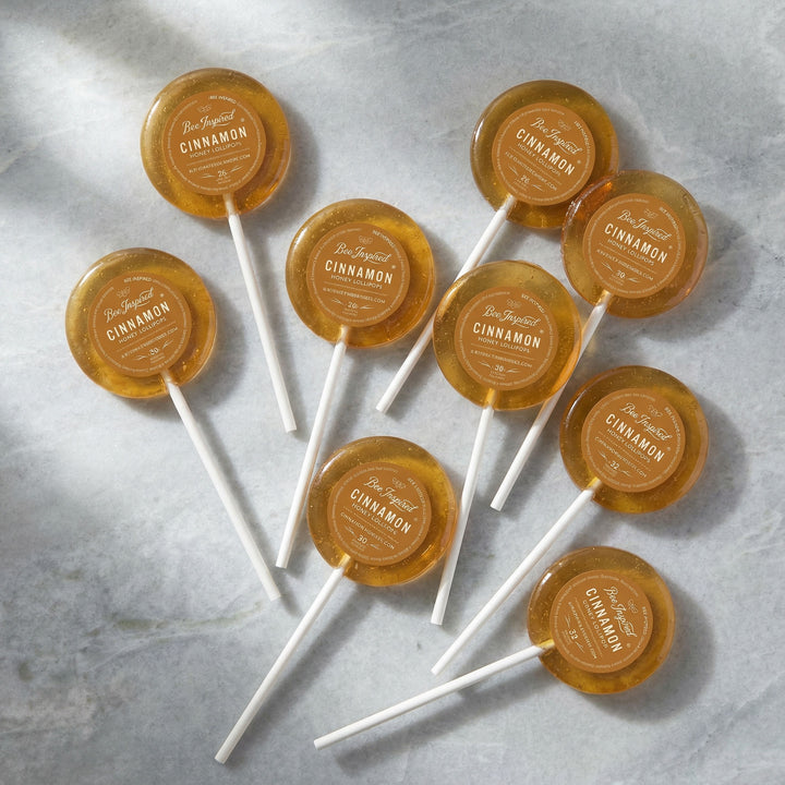 Cinnamon lollipops with labels on a gray surface