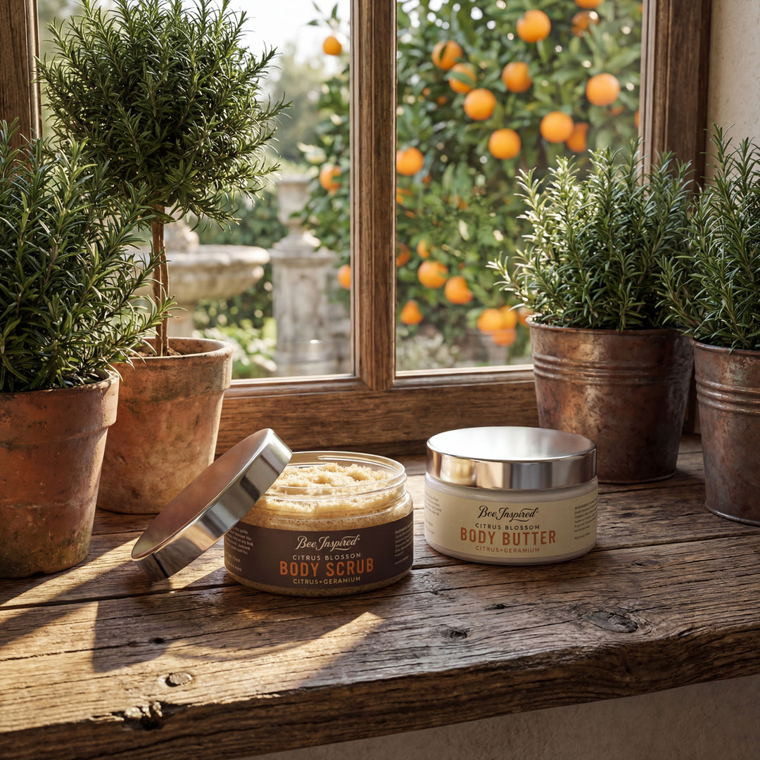 Two containers of body products on a wooden surface with plants and oranges in the background.