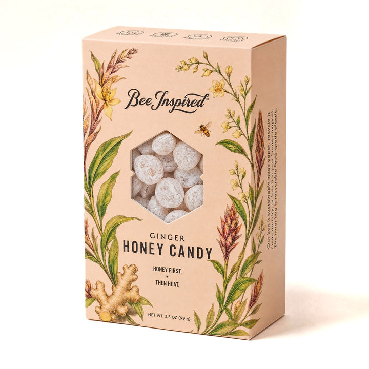 A box of Bee Inspired Ginger Honey Candy, featuring a light peach-colored packaging with botanical illustrations of ginger, honey flowers, and bees, and a hexagonal window showing the white, round candy pieces inside.
