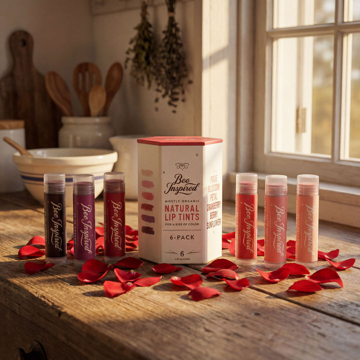 Set of lip tint tubes with a box on a wooden surface with red petals