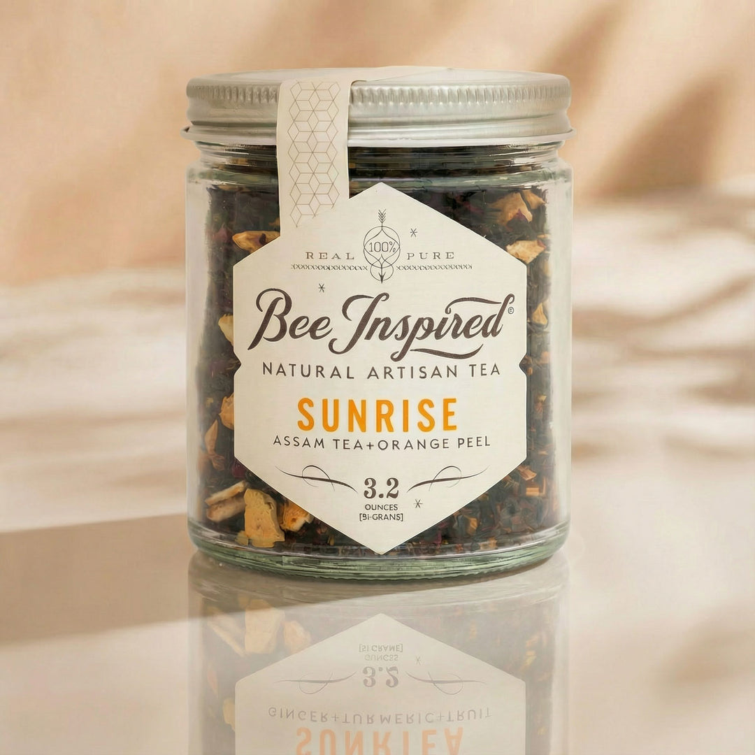 Jar of 'Bee Inspired' natural artisan tea with a label on a reflective surface.